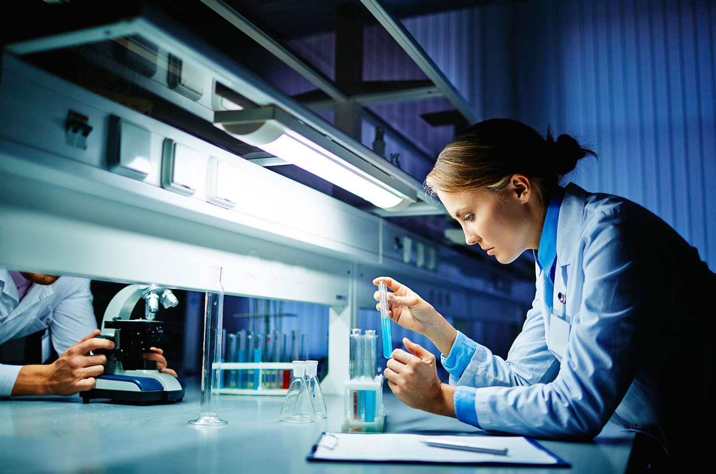 Young clinician looking at flask with liquid